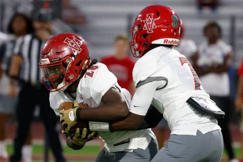 Arbor View’s quarterback Michael Kearns (7) hands off to Nylon Johnson (28) during the f ...