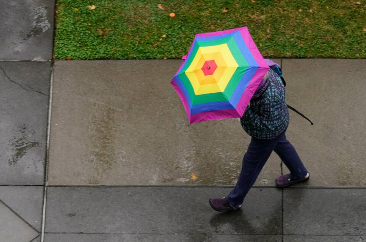 A brightly colored umbrella helps a person shield themselves from the rain in Sacramento, Calif ...