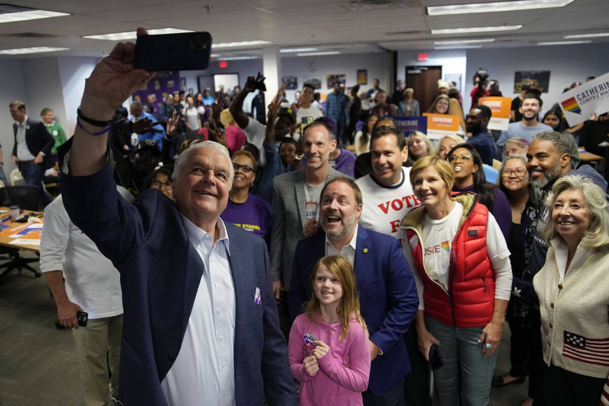 Nevada Gov. Steve Sisolak, left, takes a selfie with other candidates and supporters during a c ...