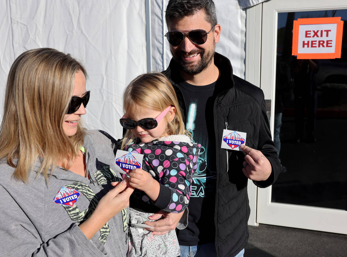 Summer and Travis Merkle of Las Vegas show their “I VOTED” stickers with their da ...