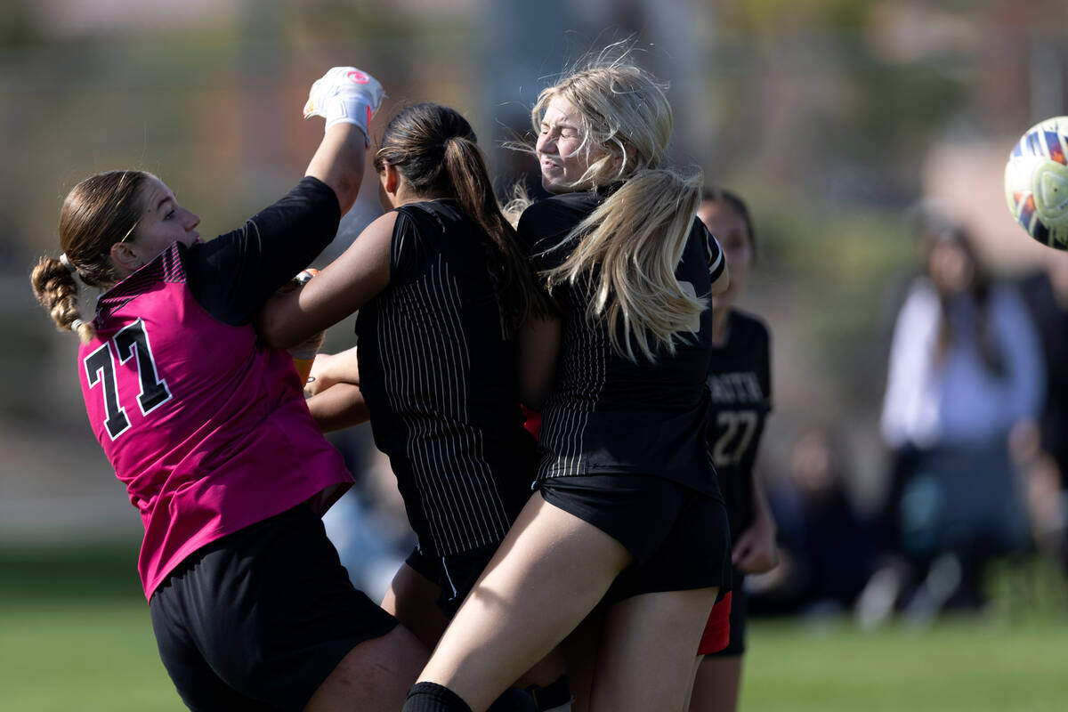 Faith Lutheran players including Elke Travis (77) and Brooklyn Mater, right, thwart a shot on g ...