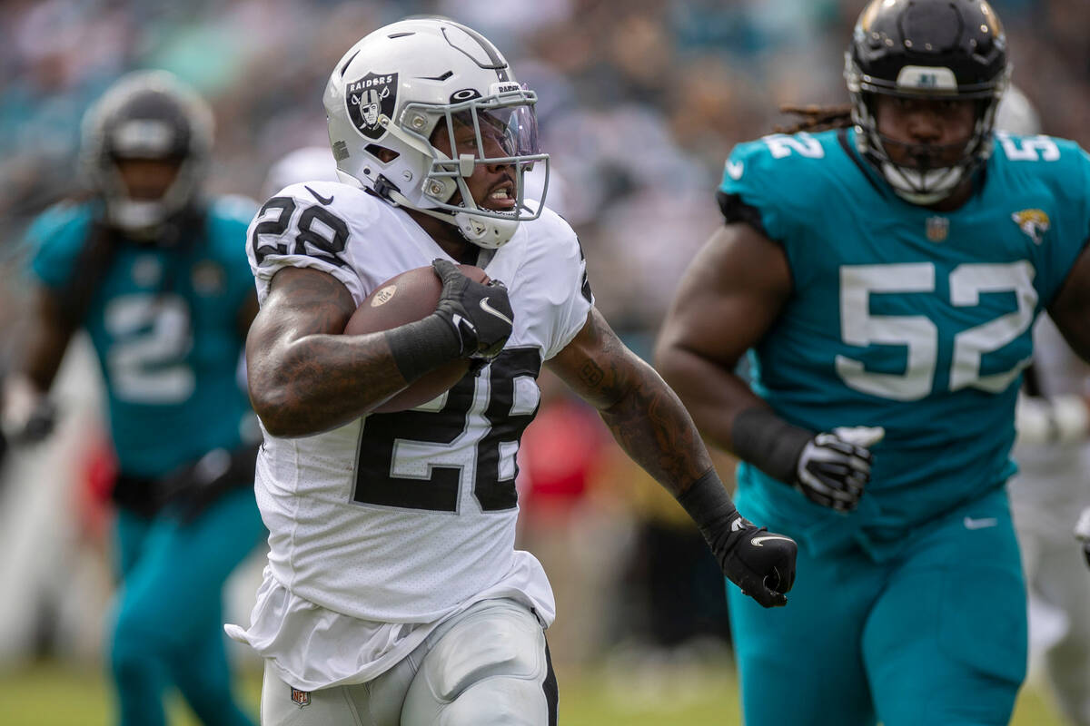 Raiders running back Josh Jacobs (28) looks for room to run with Jacksonville Jaguars defensive ...