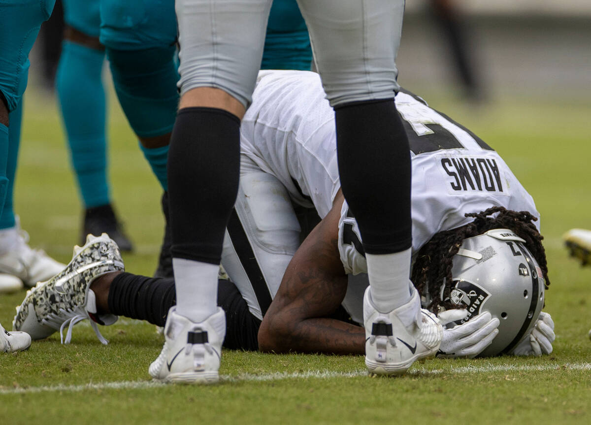 Raiders wide receiver Davante Adams (17) remains on the field after taking a hit on a play duri ...