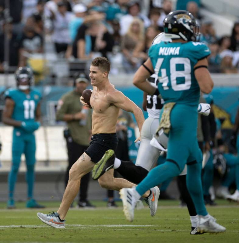 A fan runs on the field during the second half of an NFL game between the Raiders and the Jacks ...