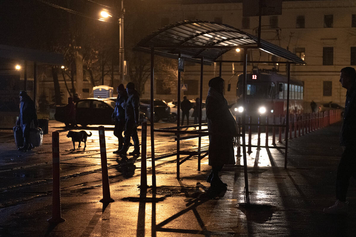People wait at a tram stop during a blackout in Kyiv, Ukraine, Sunday, Nov. 6, 2022. (AP Photo/ ...