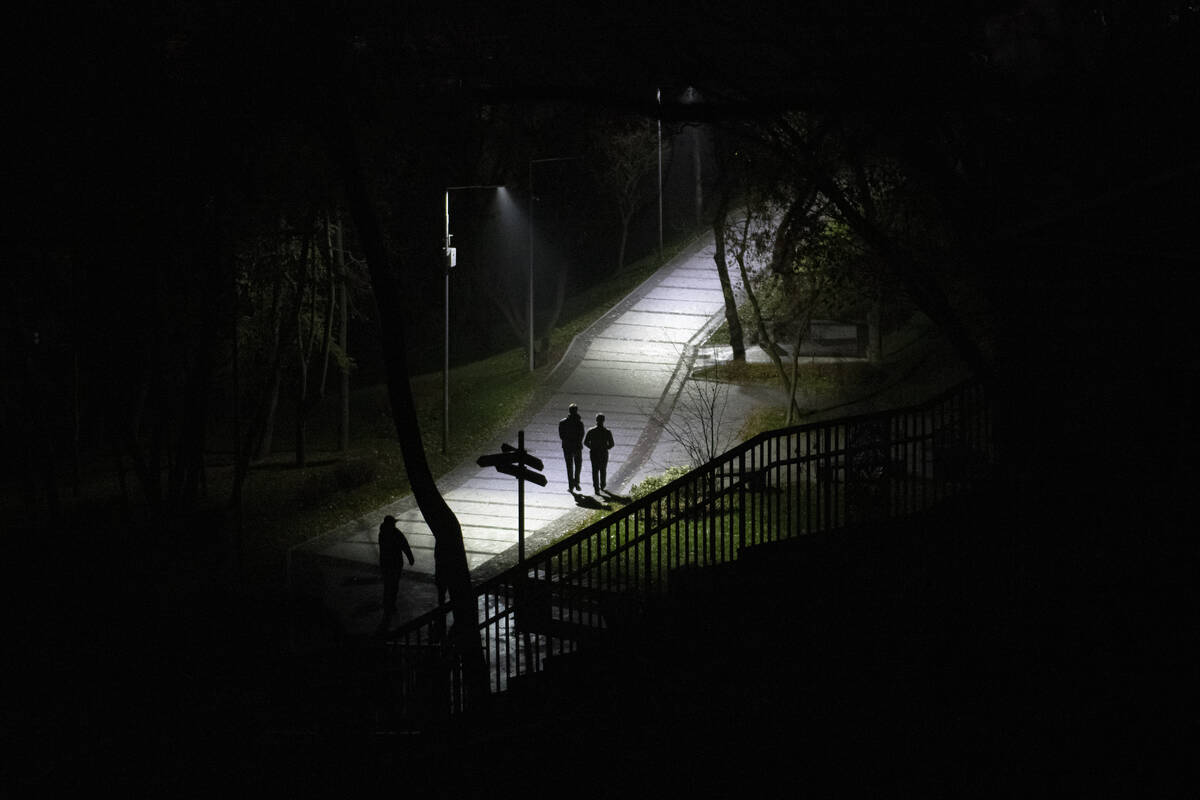 People walk in a park during a blackout in Kyiv, Ukraine, Sunday, Nov. 6, 2022. (AP Photo/Andre ...