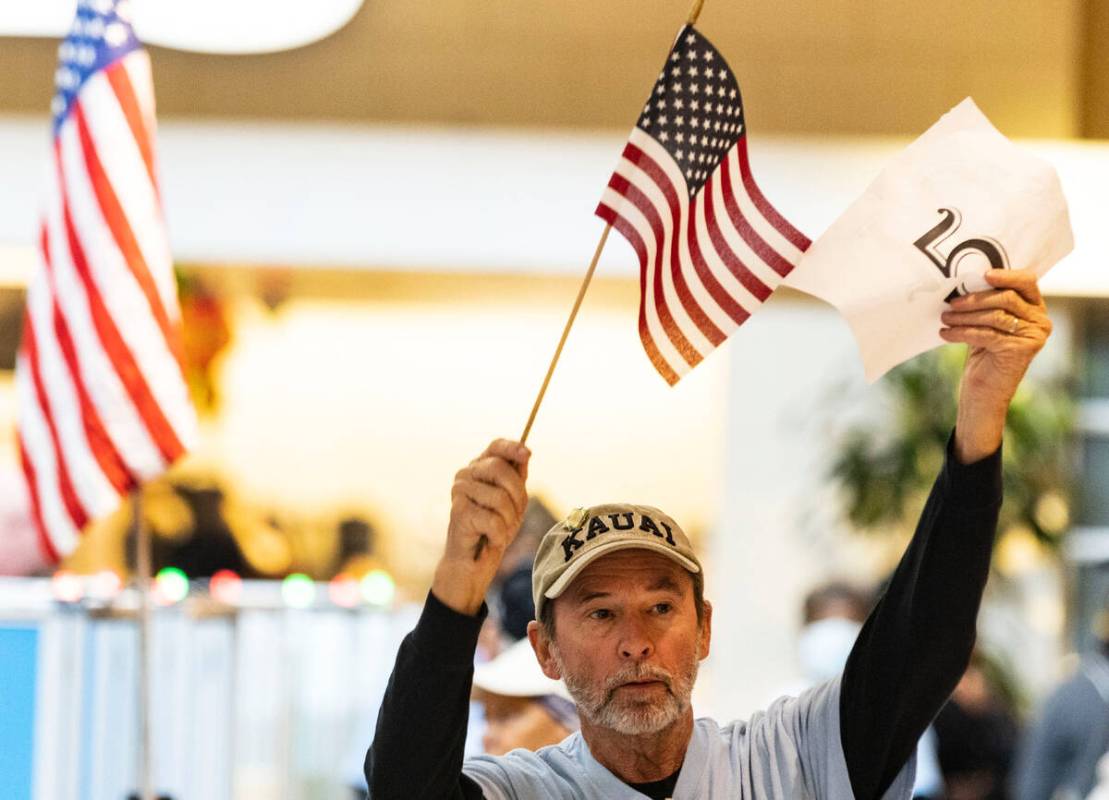 Steve Hulsizer, a volunteer, signals voters to approach the voting booths as voters line up to ...