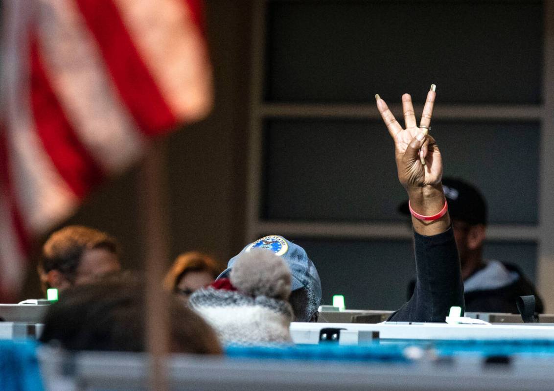 An election worker signals voters which booth is available as voters line up to cast their vot ...