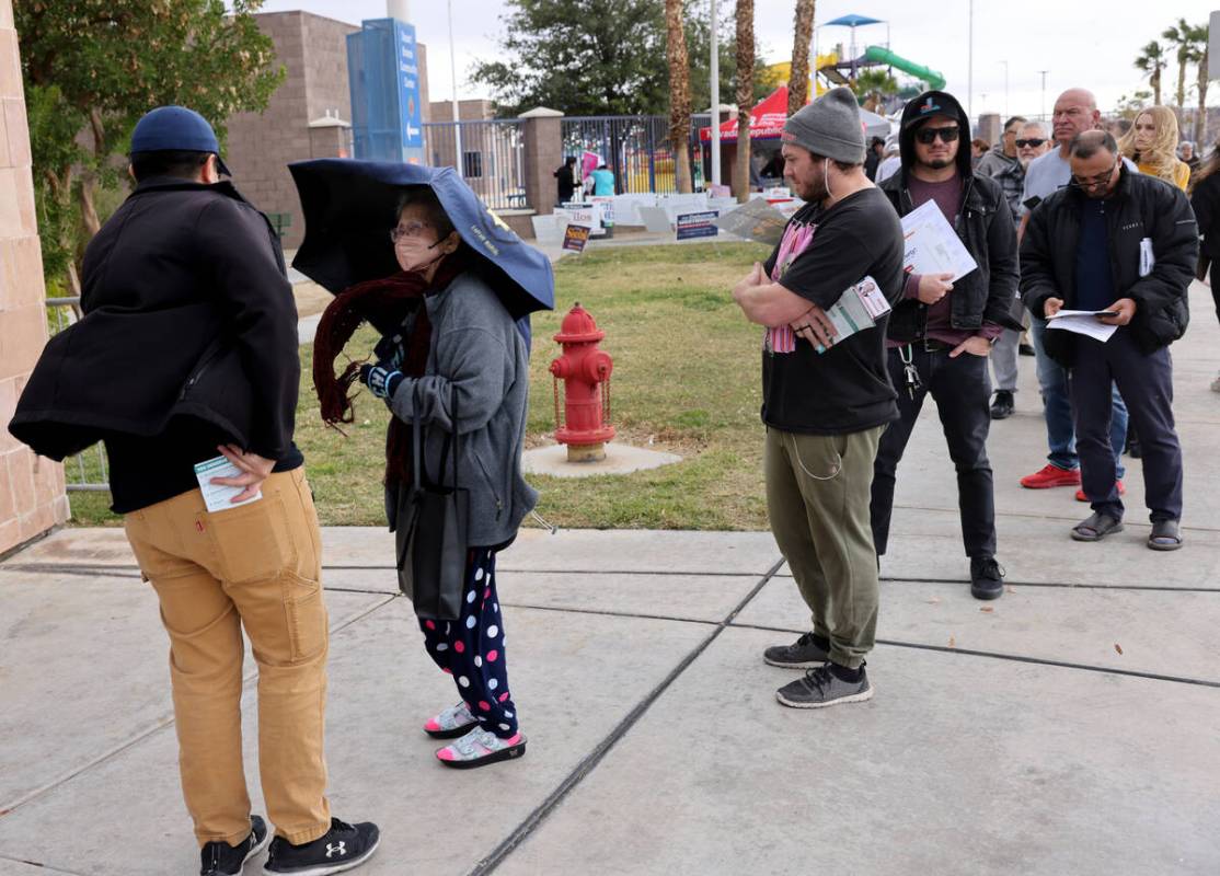 Voters brave high winds and rain drops while waiting in line on Election Day at Desert Breeze C ...