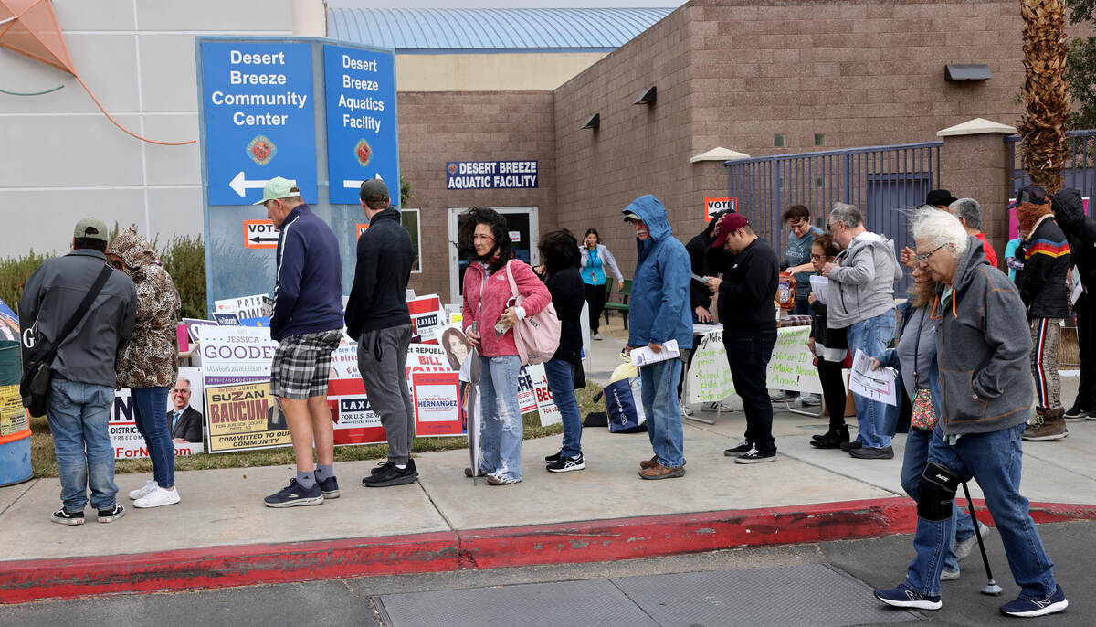Voters brave high winds and rain drops while waiting in line on Election Day at Desert Breeze C ...