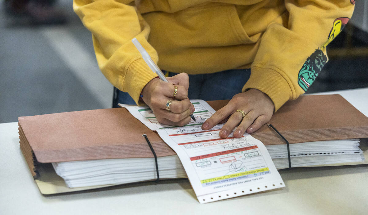 A worker signs an account form as they continue sorting ballots for final tabulations at the Cl ...