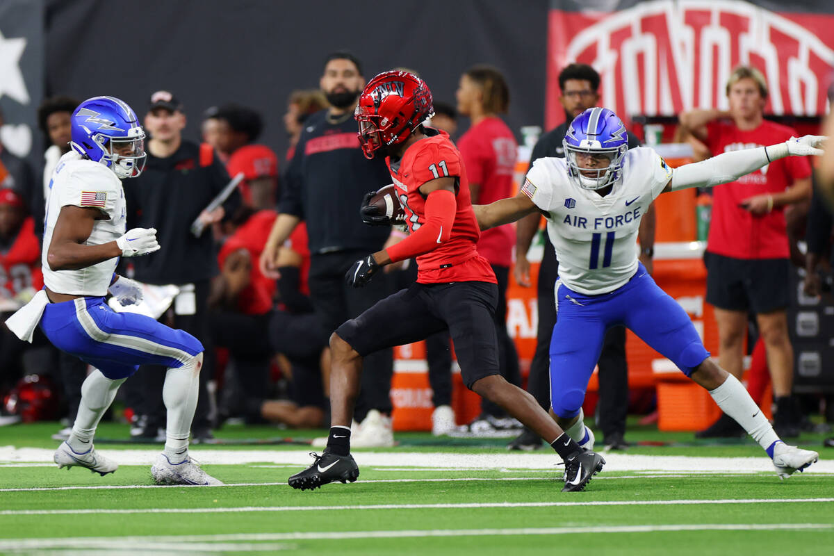 UNLV Rebels wide receiver Ricky White (11) runs the ball under pressure from Air Force Falcons ...