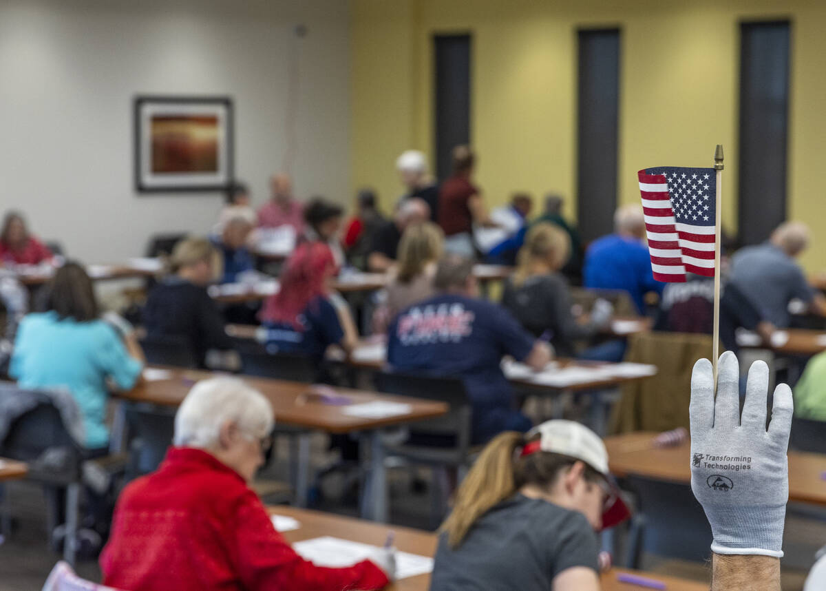 A volunteer waves a flag for ballot marking confirmation as they resume hand counting ballots i ...