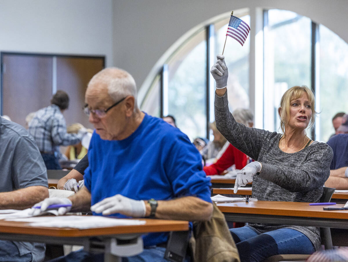 A volunteer waves a flag for ballot marking confirmation as they resume hand counting ballots i ...
