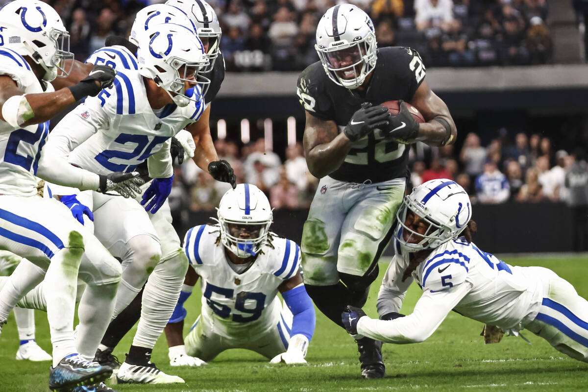 Raiders running back Josh Jacobs (28) runs the ball as Indianapolis Colts wide receiver Michael ...