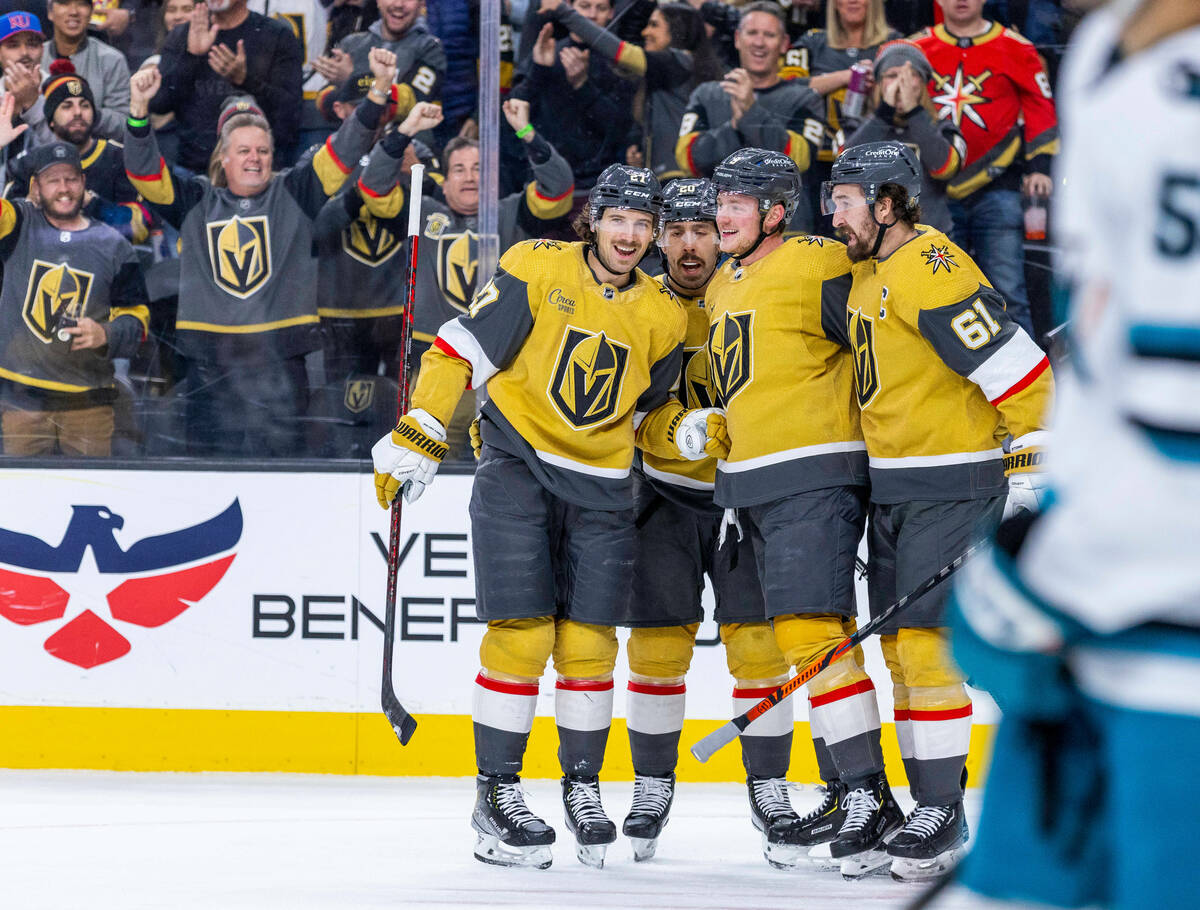 Golden Knights defenseman Shea Theodore (27) is celebrated for his score by teammates over the ...