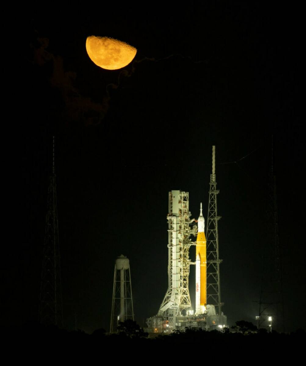 The moon rises above NASA's Space Launch System (SLS) rocket with the Orion spacecraft aboard a ...