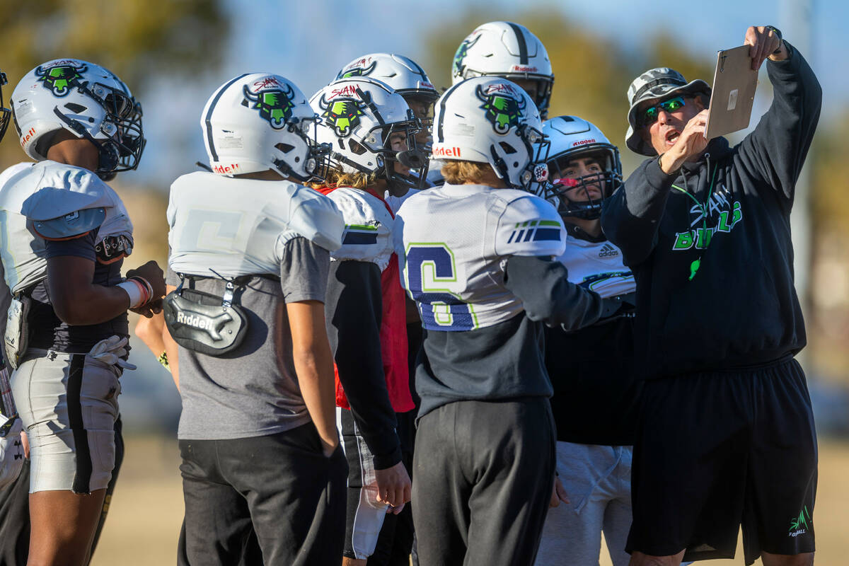 SLAM Academy Head Coach Mike Cofer reviews a formation during football practice while preparing ...