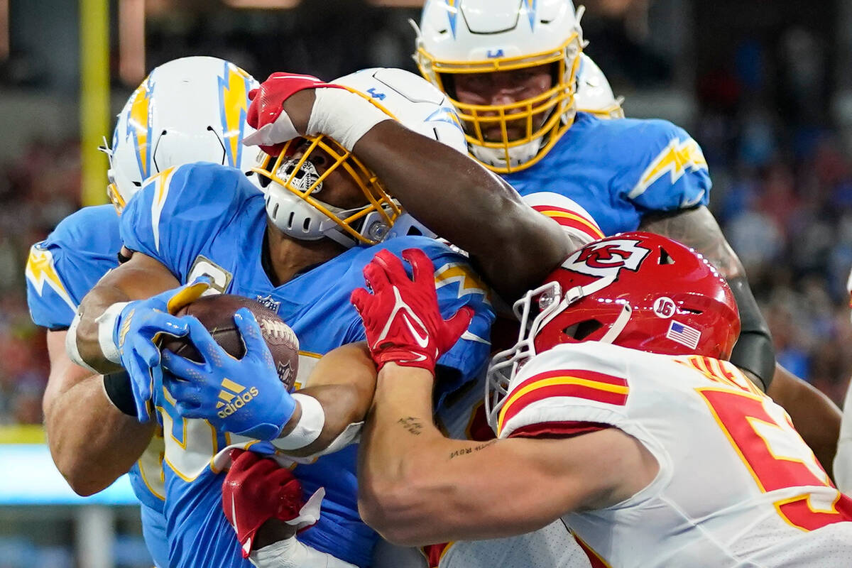 Los Angeles Chargers running back Austin Ekeler, left, scores a touchdown as he is face masked ...