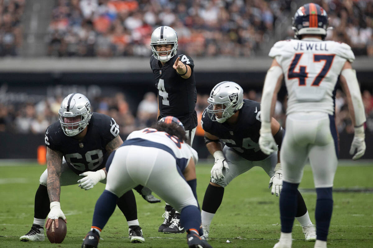 Raiders quarterback Derek Carr (4) audibles at the line of scrimmage behind center Andre James ...