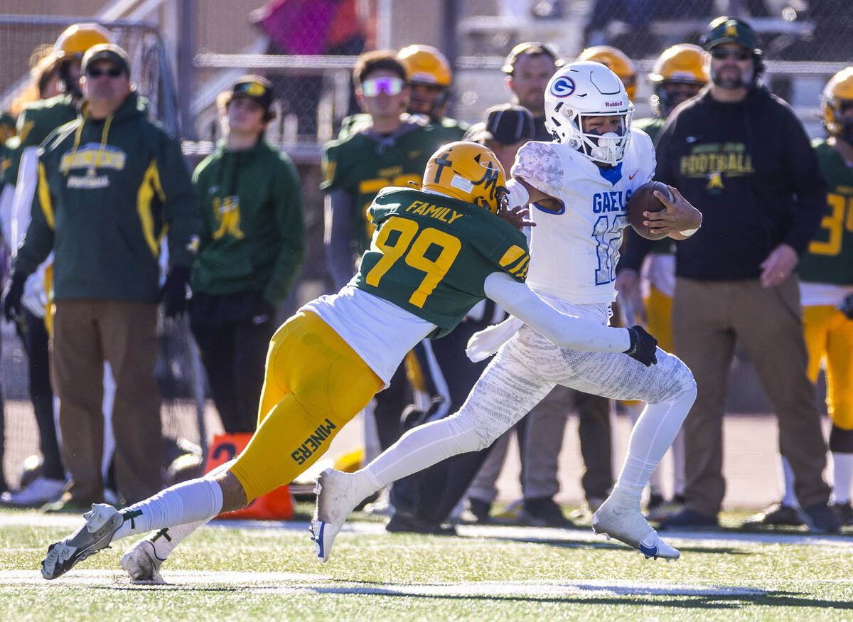 Bishop Gorman QB Micah Alejado (12) stiff arms Bishop Manogue DB Carson Jensen (99) to run down ...