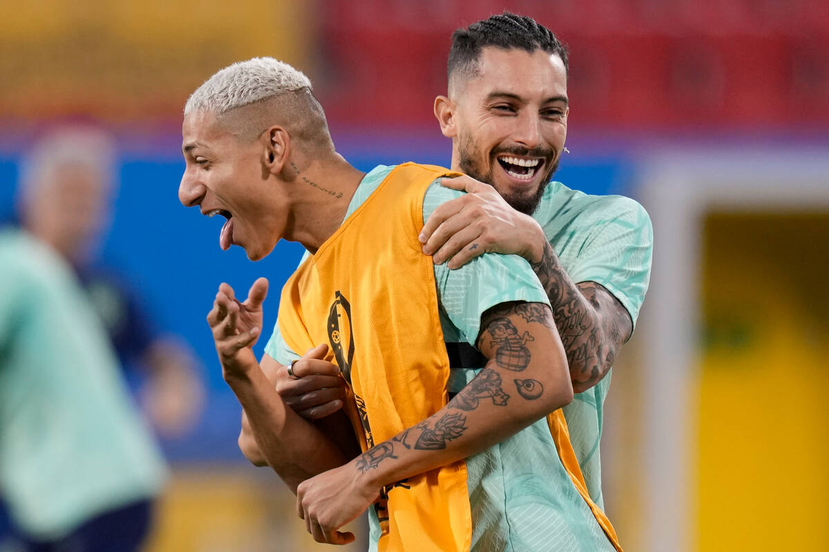 Brazil's Richarlison, left, jokes with teammate Alex Telles during a training session at the Gr ...