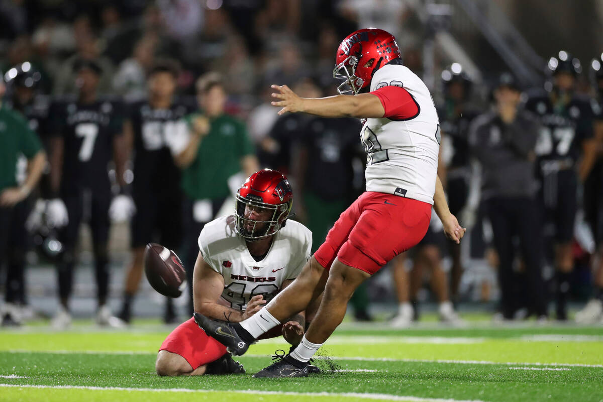 As UNLV defensive back Daego Albert (40) holds the ball, UNLV place kicker Daniel Gutierrez (32 ...