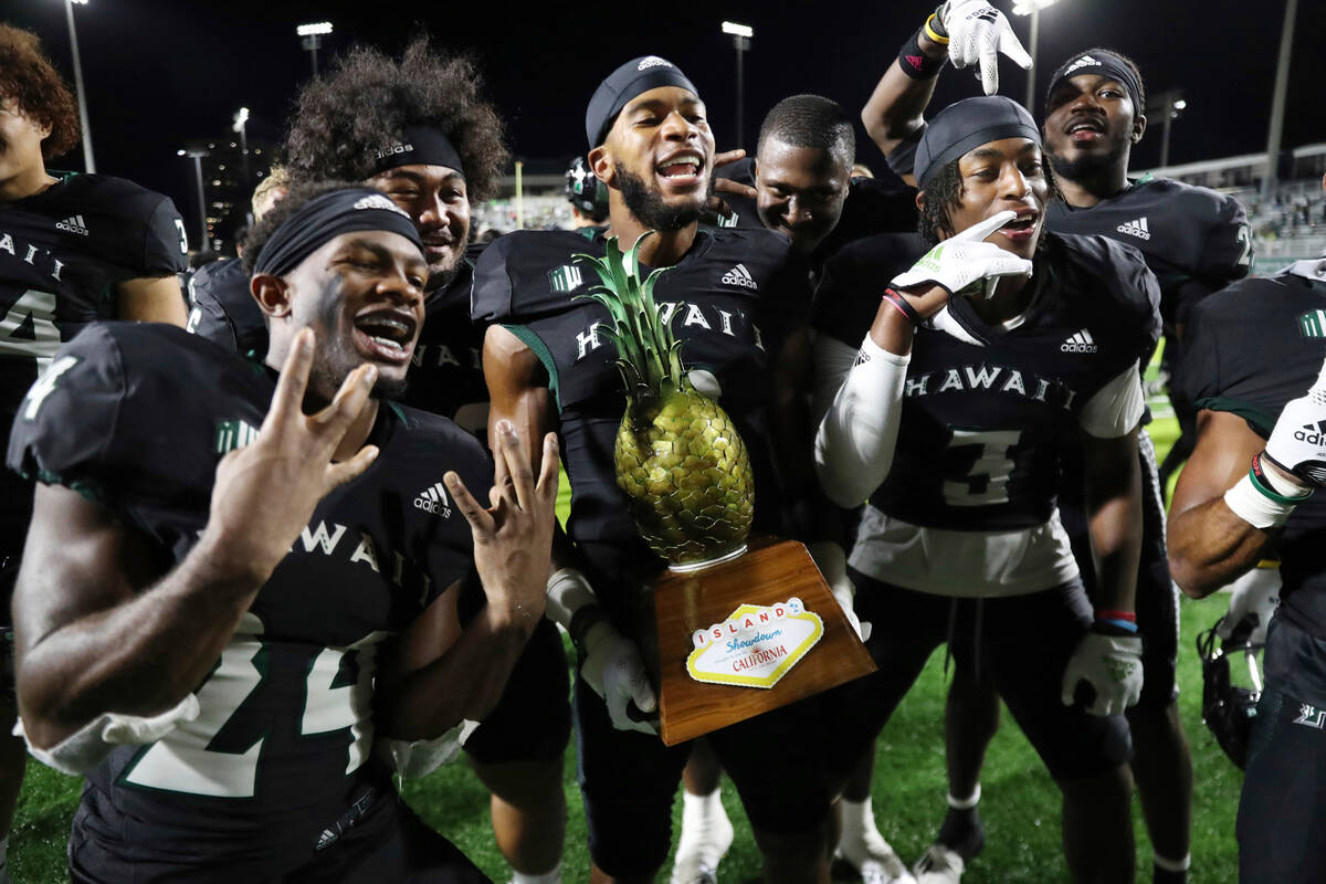 Hawaii football players hold the Island Showdown Trophy after defeating UNLV 31-25 in an NCAA c ...