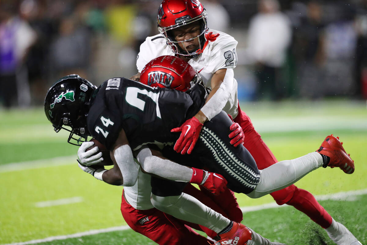 UNLV's Nohl Williams and BJ Harris (21) pull down Hawaii's Tylan Hines (24) on a punt return du ...