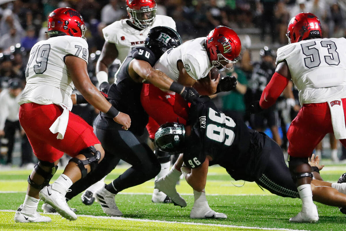 UNLV quarterback Doug Brumfield (2) is sacked by Hawaii defensive linemen John Tuitupou (90) an ...