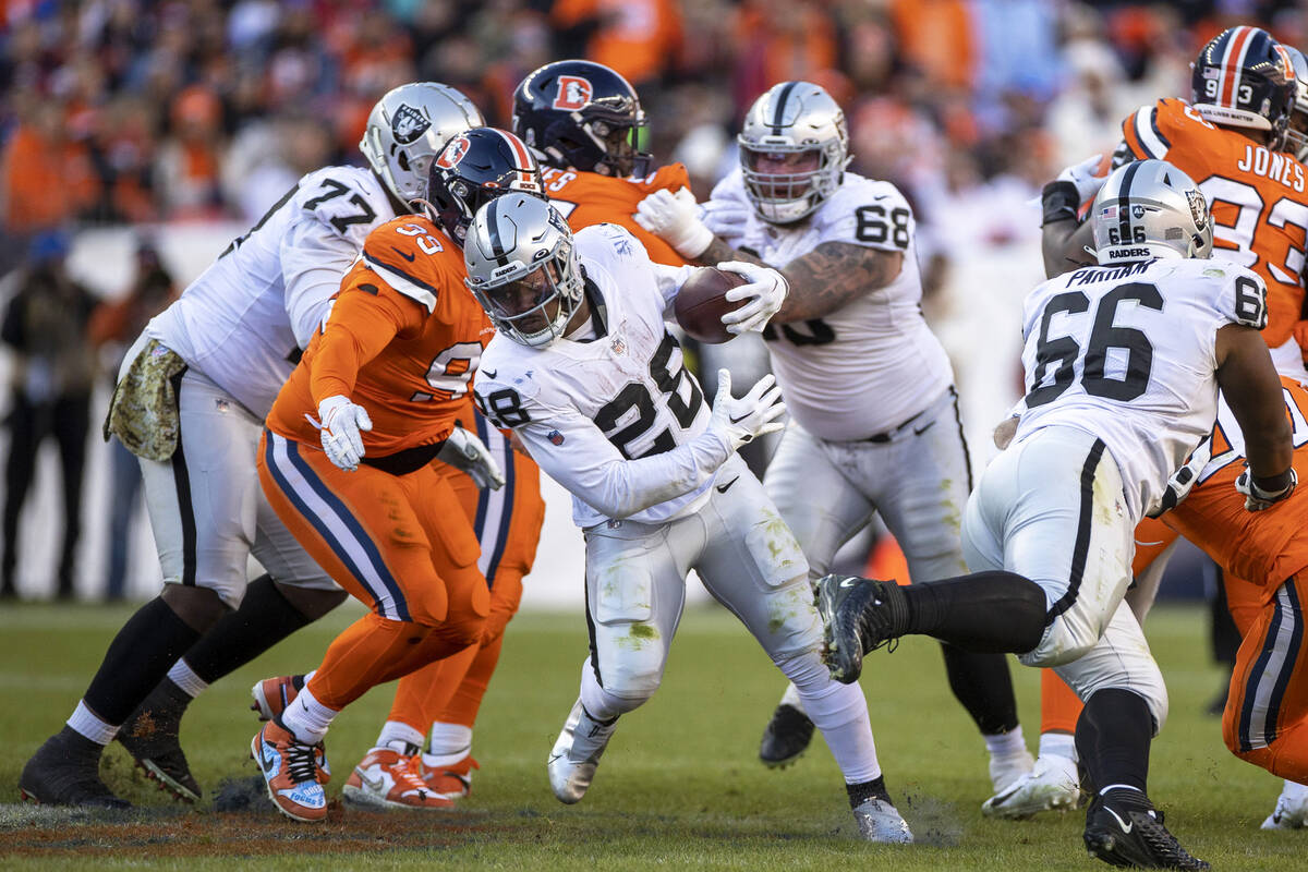 Raiders running back Josh Jacobs (28) looks for room to run against the Denver Broncos during t ...