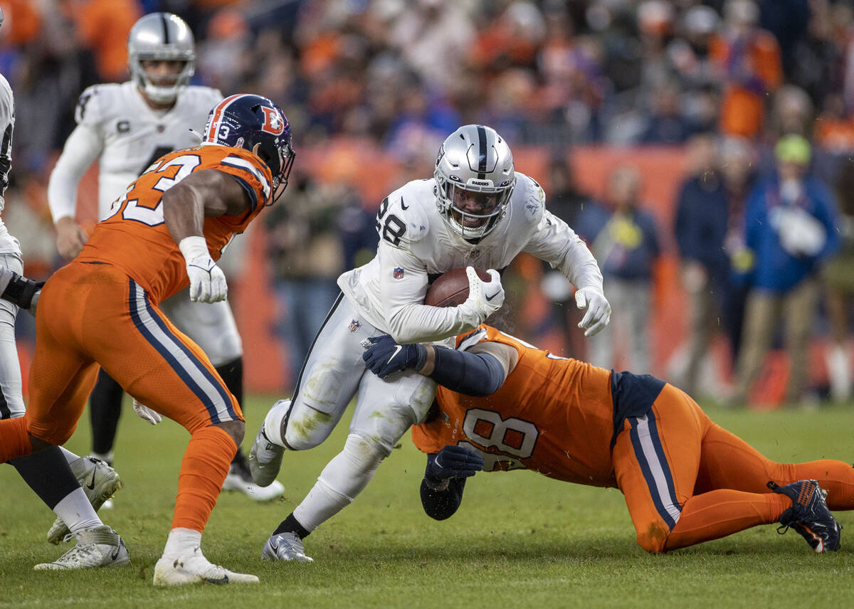 Raiders running back Josh Jacobs (28) looks for room to run against Denver Broncos defensive ta ...