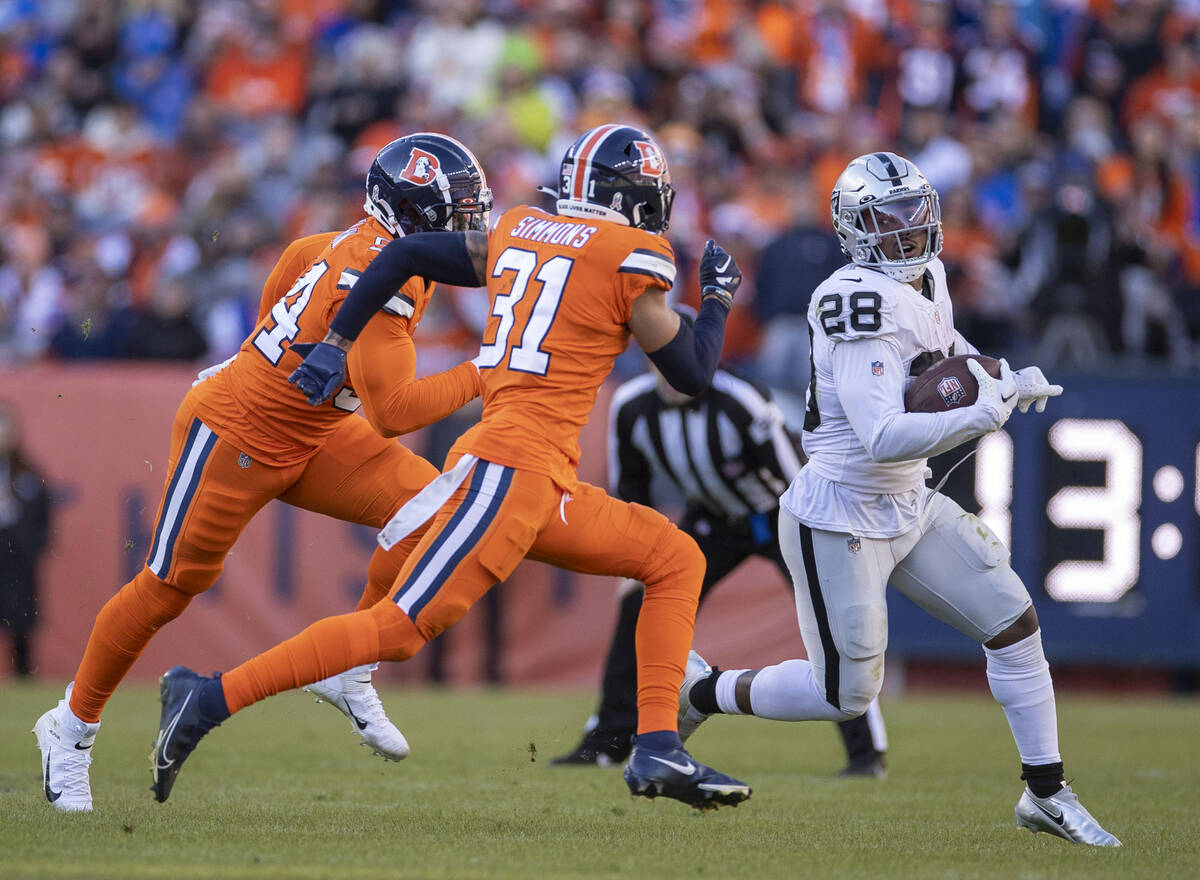Raiders running back Josh Jacobs (28) looks to escape Denver Broncos linebacker Aaron Patrick ( ...
