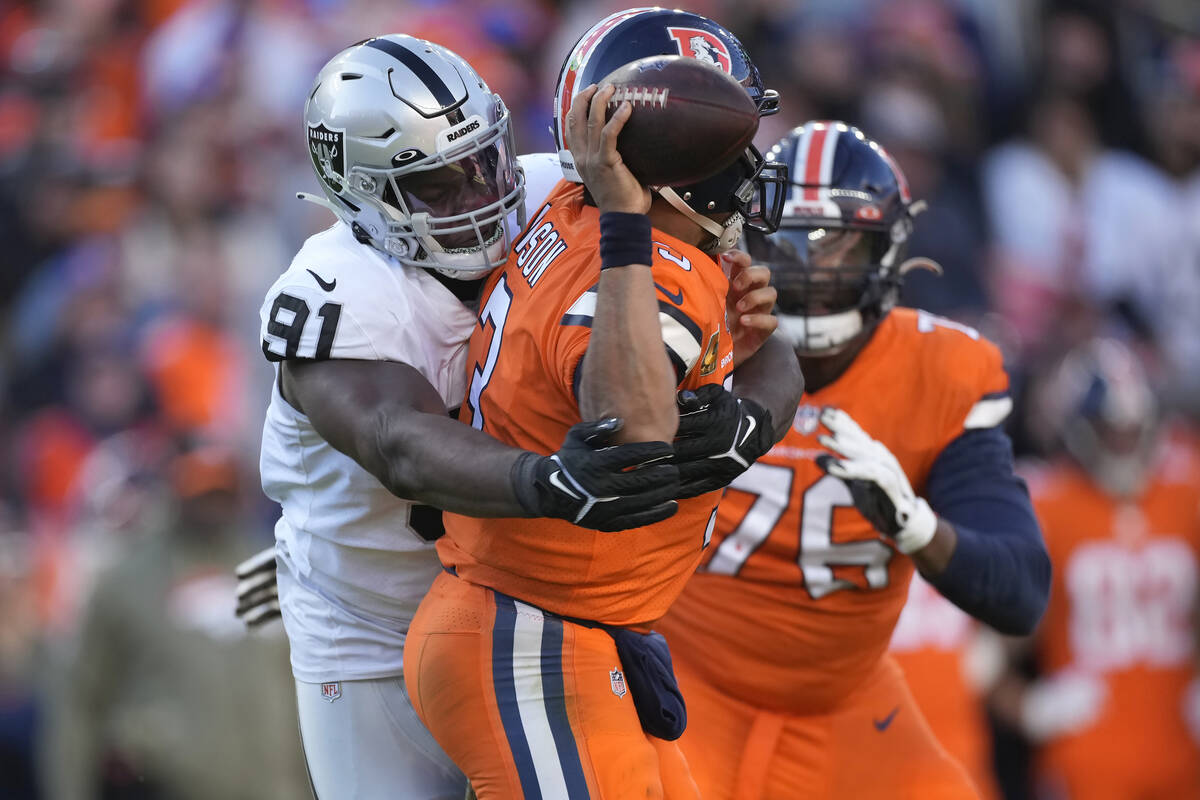 Denver Broncos quarterback Russell Wilson, middle, is hit by Las Vegas Raiders defensive tackle ...