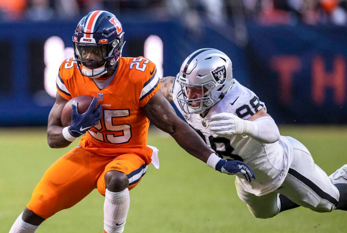 Raiders defensive end Maxx Crosby (98) lunges in to tackle Denver Broncos running back Melvin G ...