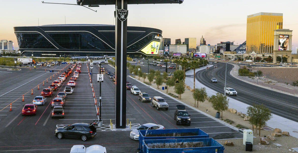 Cars weave their way around Allegiant Stadium as Raiders' current and former players along with ...