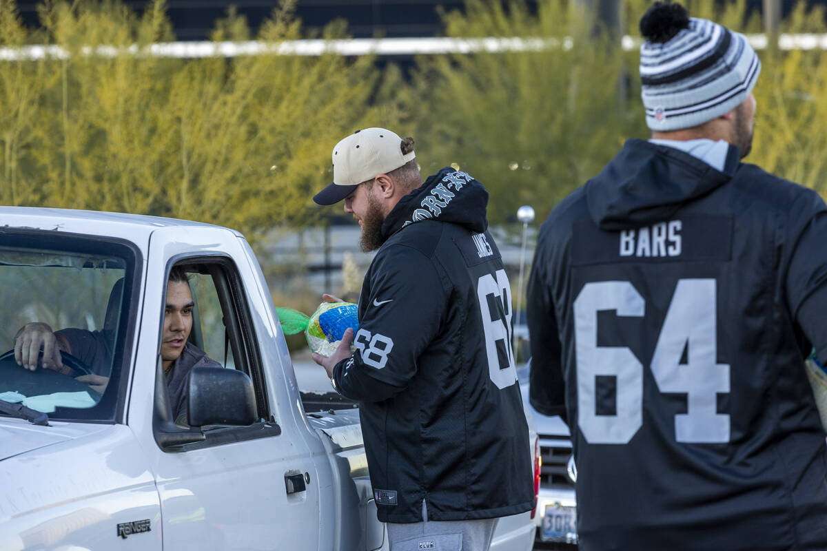 Raiders center Andre James (68) delivers a turkey with guard Alex Bars (64) nearby as they joi ...