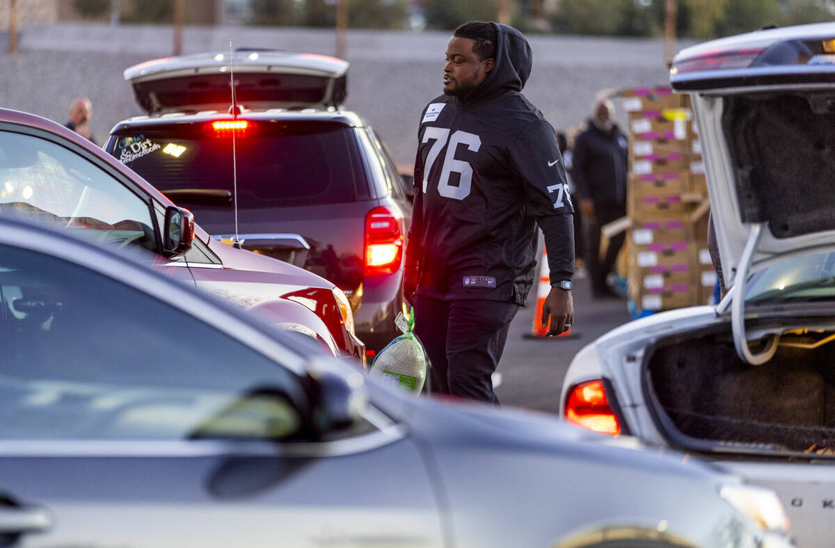 Raiders guard John Simpson (76) delivers a turkey as Raiders' current and former players along ...