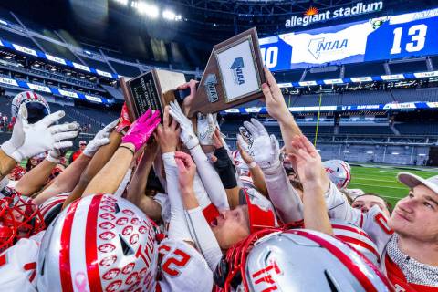 Truckee Head Coach Josh Ivens is nearly swallowed up as he celebrates the winning trophy with h ...