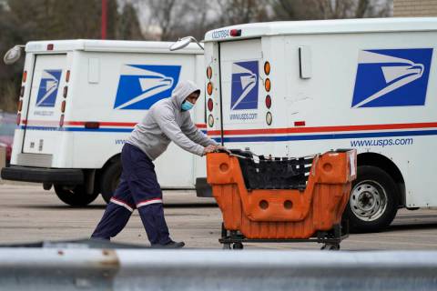 A United States Postal Service employee works outside a post office in Wheeling, Ill., Dec. 3, ...