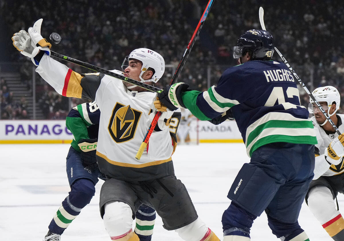 Vegas Golden Knights' William Carrier, left, and Vancouver Canucks' Quinn Hughes (43) vie for t ...