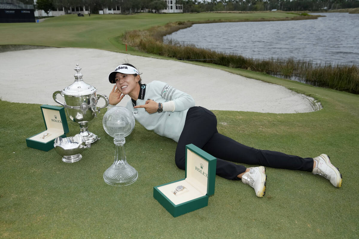 Lydia Ko, of New Zealand, poses with the Rolex Player of the Year trophy, left, the Vare trophy ...