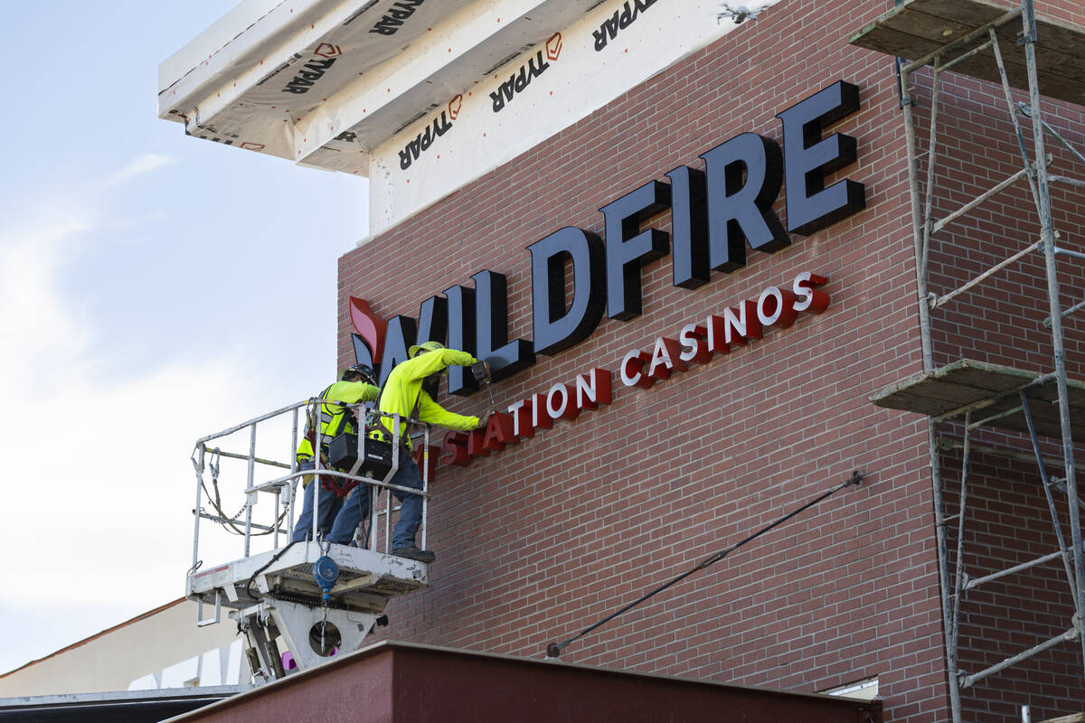 Jeremy Jewell, left, and Dean Corbin of Hartlauer Signs install signage for the new Wildfire Ca ...
