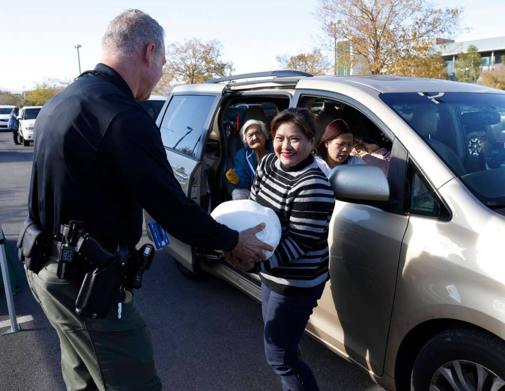 Metro police officer T. Howell hands out free turkey to a family for a Thanksgiving meal outsid ...