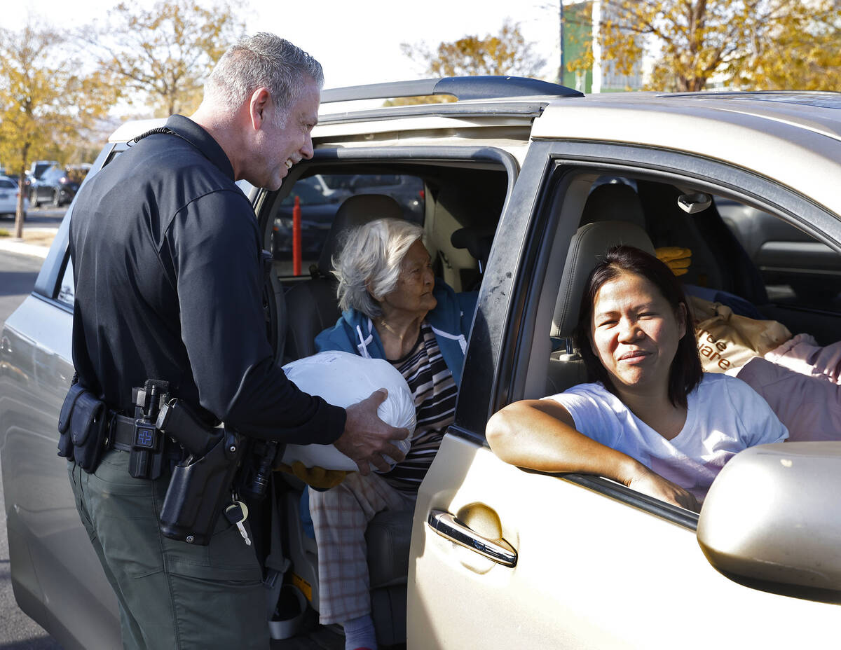 Metro police officer T. Howell hands out free turkey to a family for a Thanksgiving meal outsid ...