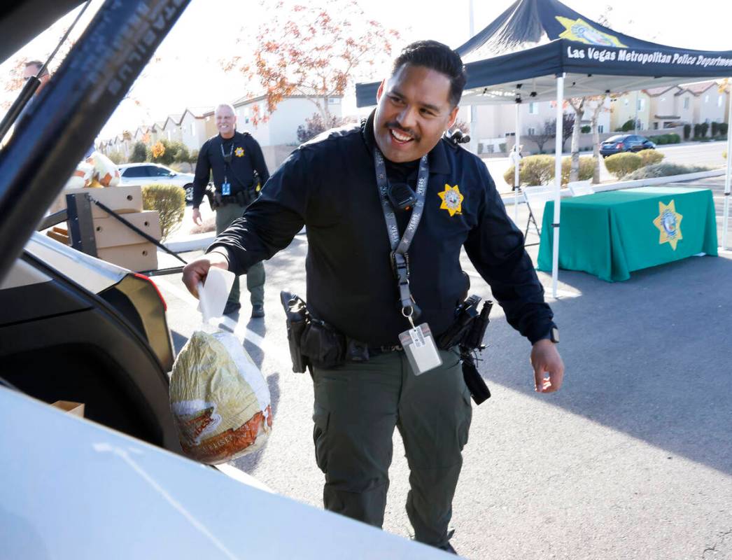 Metro police officers T. Howell, left, watches as officer W. Sumalpong load free turkey into a ...