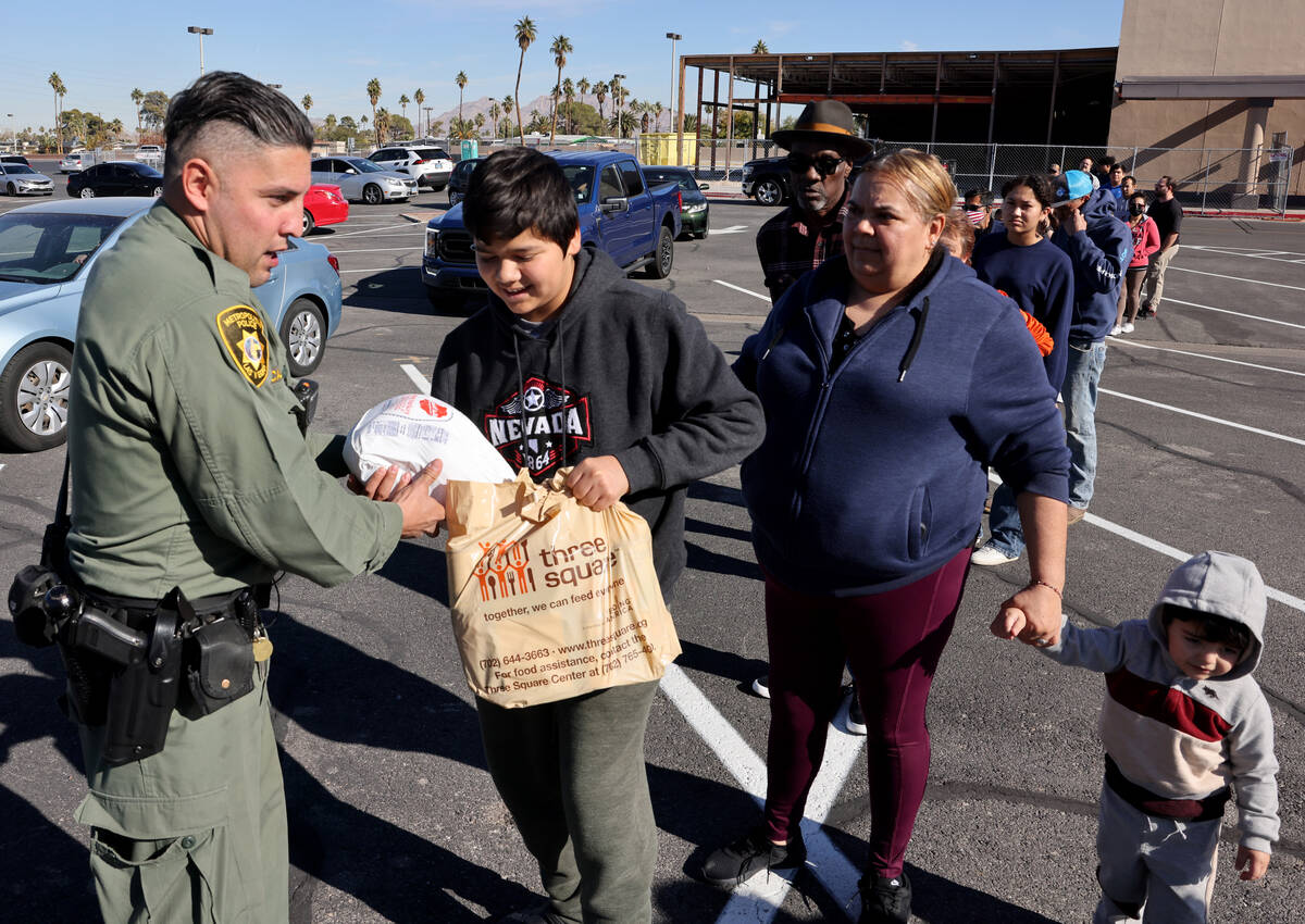 Las Vegas police officer Alfredo Calata give Thanksgiving meals to families at Boulevard Mall i ...