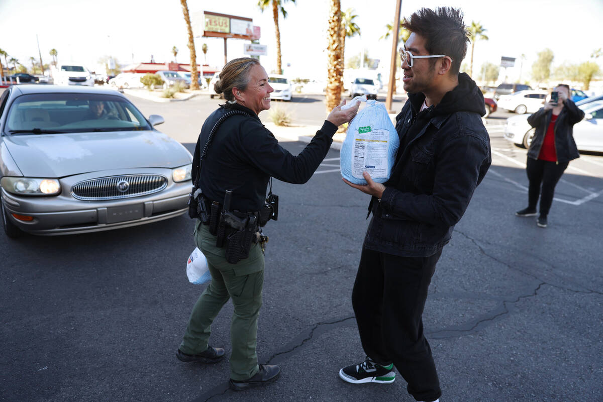 Police officer Deborah Rinkovsky, left, gives away a turkey to Jake Wang of Las Vegas during a ...