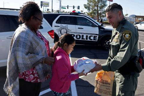 Las Vegas police officer Alfredo Calata gives a Thanksgiving meal to Maria Archille and her dau ...