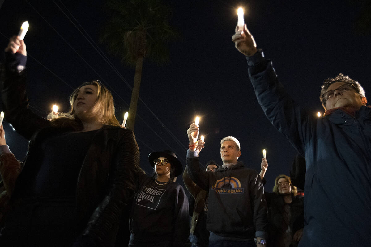 Members of the queer community and allies hold their candles to the sky during a vigil at the L ...